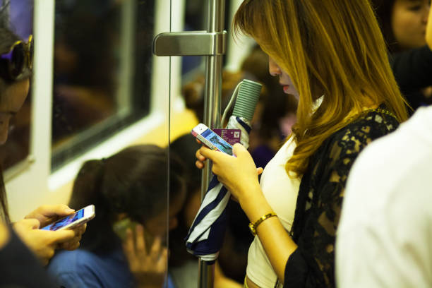 thai filles à l'aide de téléphones mobiles et facebook de métro bts - editorial iphone train city photos et images de collection