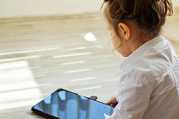 istock Little girl using digital tablet on the parquet floor. 468247570