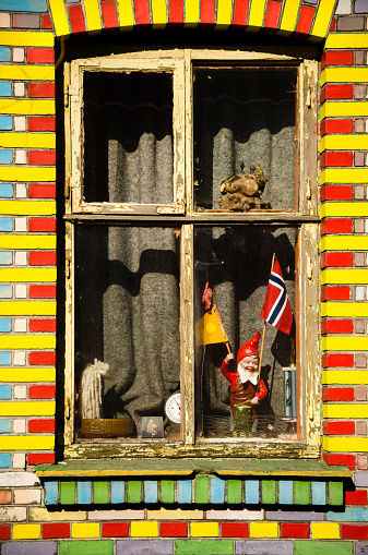 Copenhagen, Denmark - April 02, 2013: A window decorated with tiles in yellow and red, Christiania flag's colours. A garden gnome holding a Norwegian flag stands out through the glass. It is thought that one-third of the commune's inhabitants are foreigners.