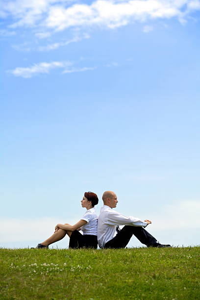 istock Business couple sitting back to back on grass 468265180