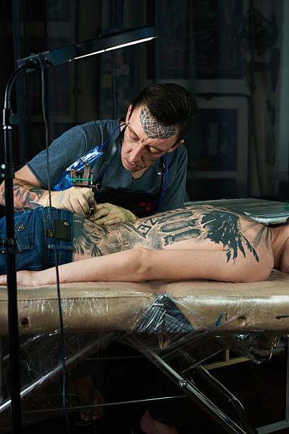 Tattoo artist creating a tattoo Tattoo artist creating a tattoo in his studio shoulder tattoo designs for men stock pictures, royalty-free photos & images
