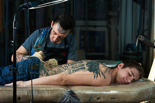 Tattoo artist draw tattoo in studio Tattoo artist draw tattoo in his studio shoulder tattoo designs for men stock pictures, royalty-free photos & images