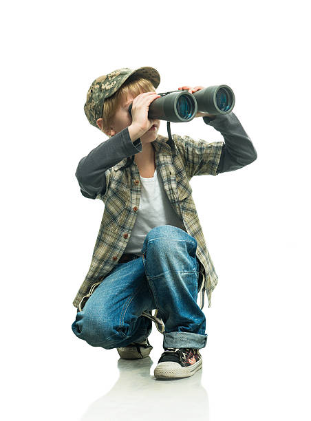 Young boy using binoculars on white background stock photo