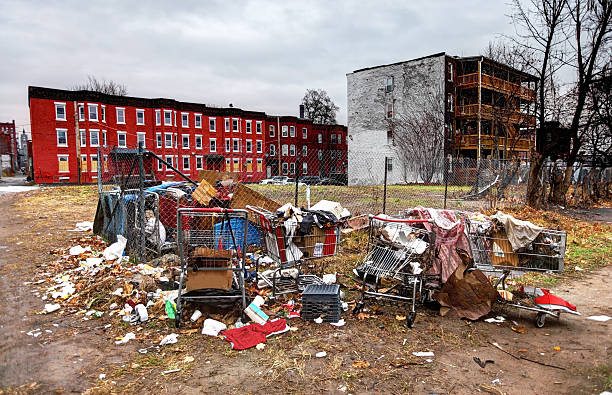 Urban Slum Trash filled vacant lot in a run down inner city urban neighborhood in Holyoke, Massachusetts surrounded by large brick tenements. American inner cities remain concentrations of poverty, homelessness, unemployment, illness and drugs. run down neighborhood stock pictures, royalty-free photos & images