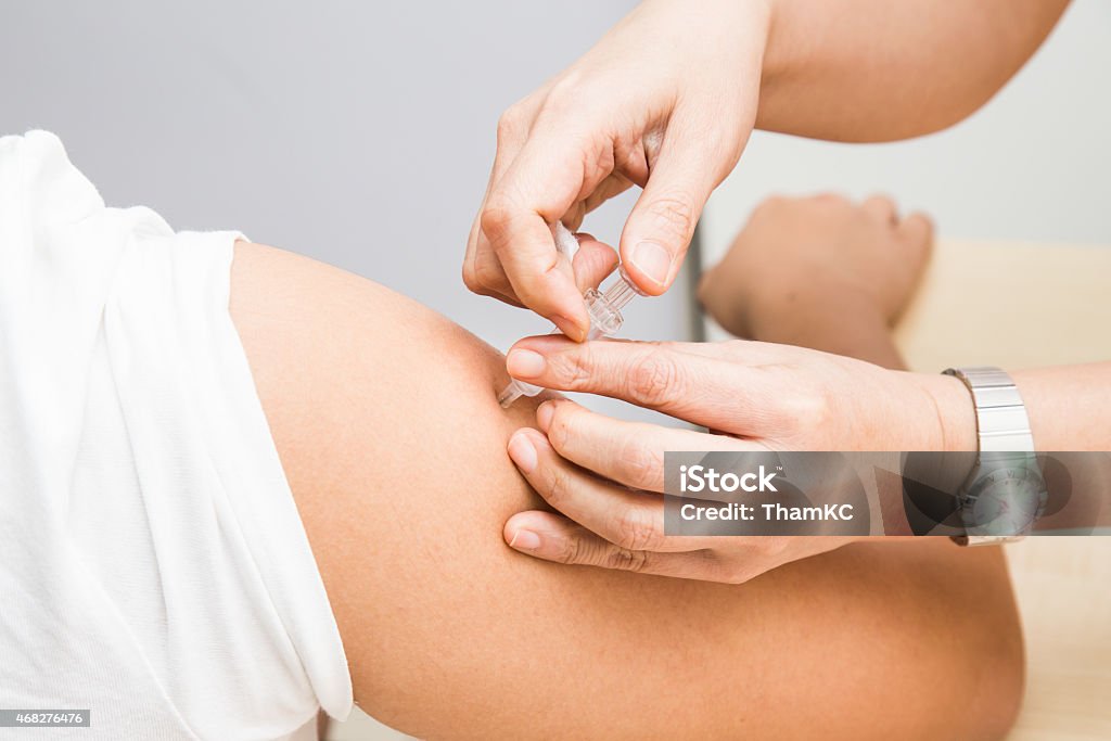 Medical doctor penetrated whole syringe into arm of patient Medical doctor penetrated whole syringe into arm of patient with the thumb getting ready to inject the vaccines. 2015 Stock Photo