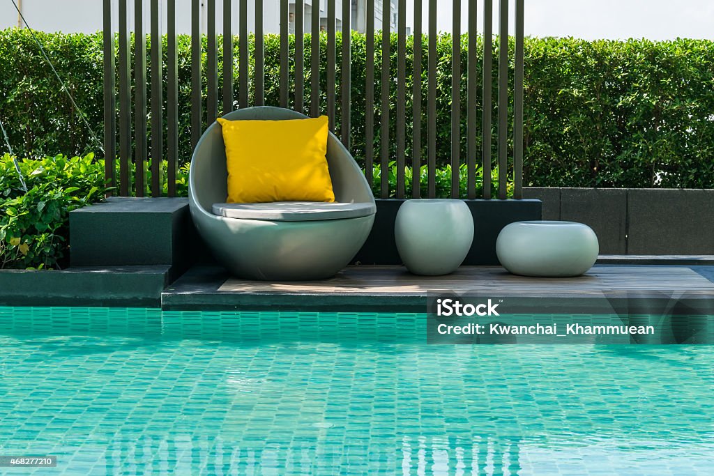 Relaxing chairs with pillows beside swimming pool Swimming Pool Stock Photo