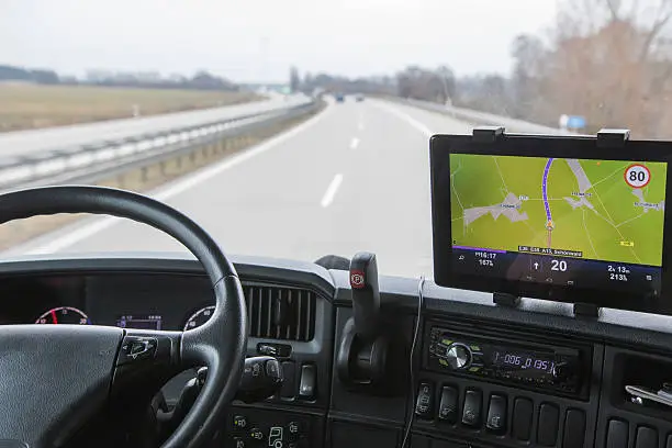 View of highway traffic through the windshield of the truck cab. Navigation is mounted on the dashboard.