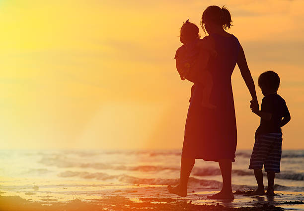 istock mother and two kids walking at sunset 468290954