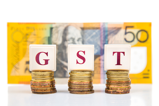 GST or Goods and Services Tax concept with a stack of coin and Australian Dollar at the background
