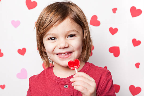 笑う少年ヴァレンティーヌキャンディーお楽しみいただけます。 - child valentines day candy eating ストックフォトと画像