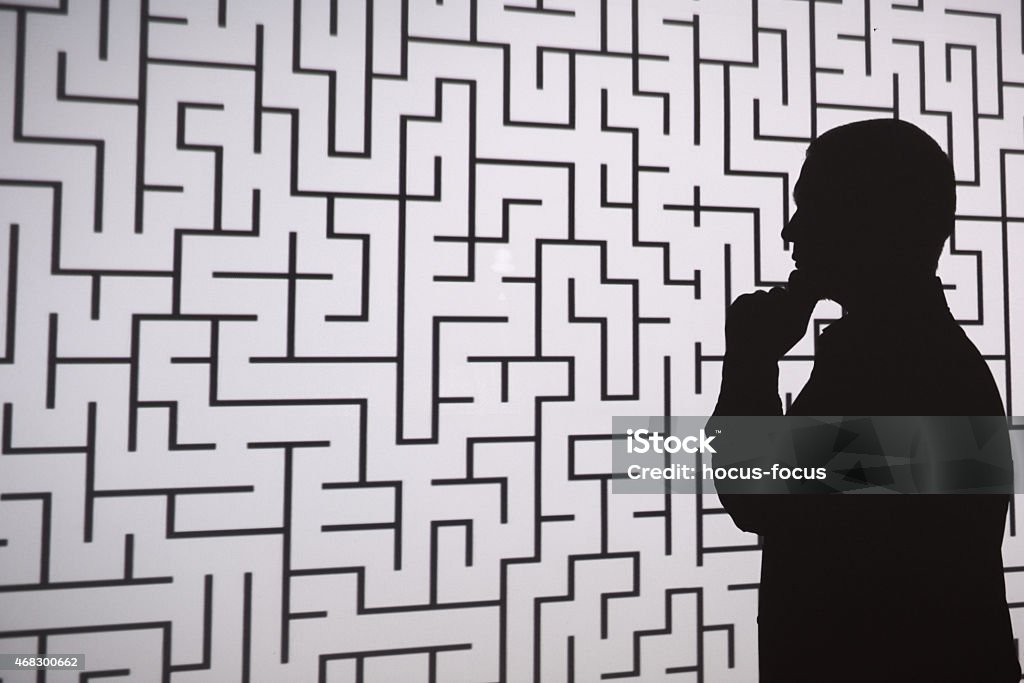 Man silhouette in front of labyrinth Businessman standing in front of projection screen. Projector reflects a labyrinth to screen..  In Silhouette Stock Photo