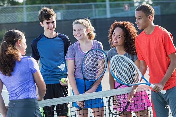 Teenagers playing tennis Multi-ethnic teenagers playing tennis.  14 to 17 years. teenagers only stock pictures, royalty-free photos & images