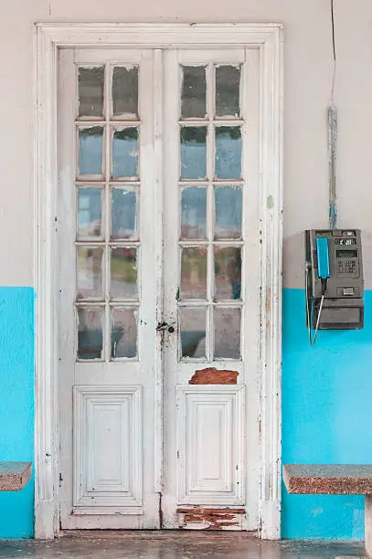 Old white doors with turquoise walls and an old phone box in Cuba