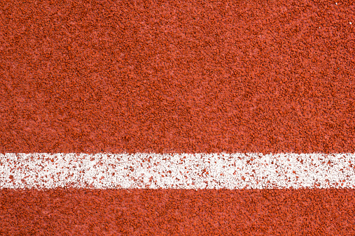 Running track with white striped on redbrick color background.