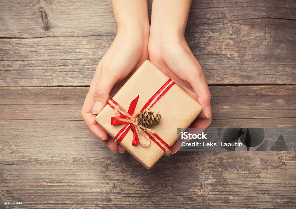 Holding a gift box Hands holding gift box with pine cone 2015 Stock Photo