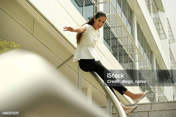 Cheerful Business Woman Going Downstairs Sliding On Rail For Joy Stock Photo - Download Image Now