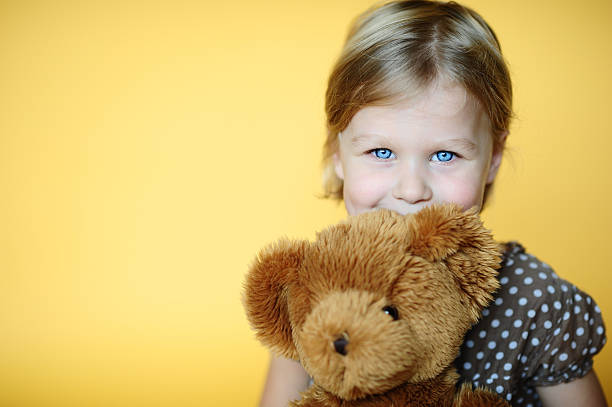 istock Girl with teddy bear on yellow background 468331646