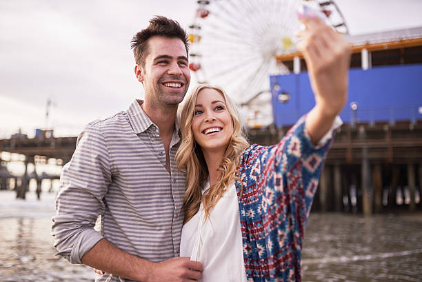 romantique couple prenant mentionné les selfies ensemble de santa monica - ferris wheel flash photos et images de collection