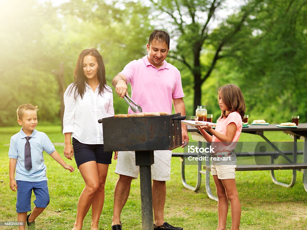 dad grilling food dad grilling food for wife and kids at outdoor cookout Barbecue - Meal Stock Photo