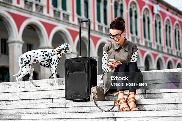 Woman Sitting On Outdoor Steps With Suitcase And Dalmatian Stock Photo - Download Image Now