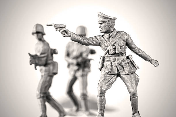 German soldier reenactment war concept with little toy soldier Concept of leadership and war, with little gray plastic soldier toy armed, german Wermacht officer and army soldier in uniform from the second world war, in selective focus. Horizontal macro shot againt clean white background with vignette and slightly sepia toned image. fascism photos stock pictures, royalty-free photos & images
