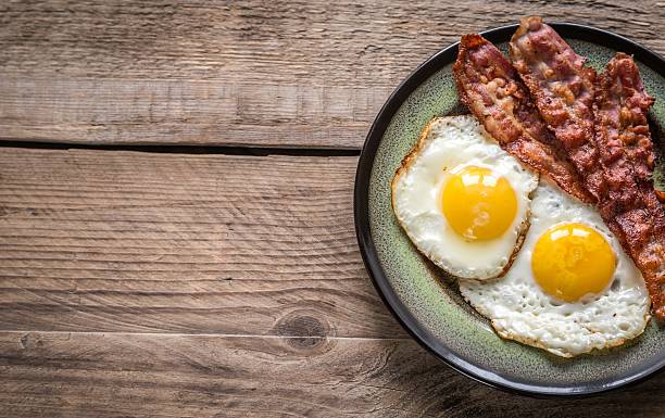 Close up of 2 sunny side up style eggs and bacon on a plate stock photo