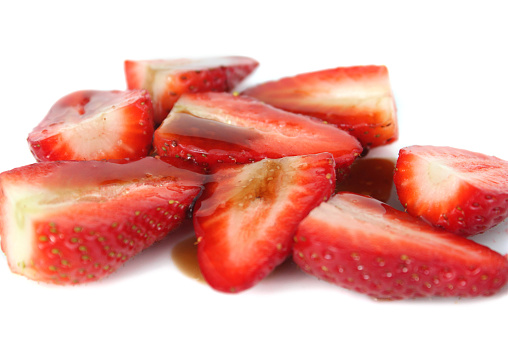 Photo showing a dish of sliced strawberries, which have been drizzled with balsamic vinegar and sprinkled with a little brown sugar.  Strawberries with balsamic vinegar is considered to be something of a 'gourmet dessert' way to eat these tasty, juicy summer fruit berries, helping to enhance the flavour.