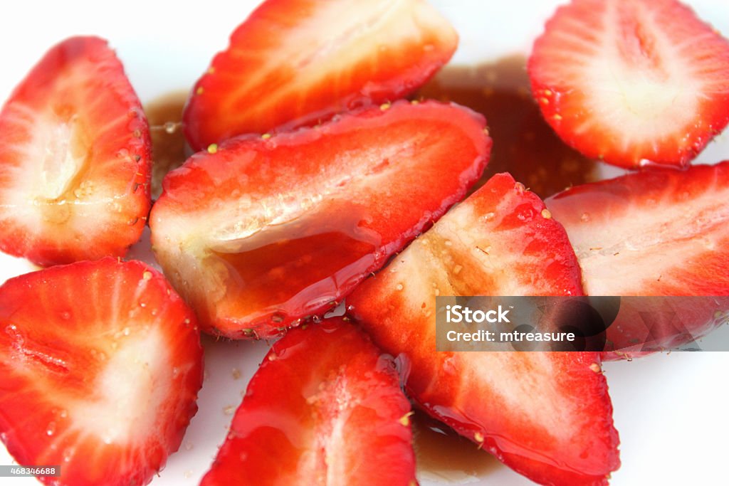 Image of sliced strawberries with balsamic vinegar and sugar, summer-fruit Photo showing a dish of sliced strawberries, which have been drizzled with balsamic vinegar and sprinkled with a little brown sugar.  Strawberries with balsamic vinegar is considered to be something of a 'gourmet dessert' way to eat these tasty, juicy summer fruit berries, helping to enhance the flavour. 2015 Stock Photo