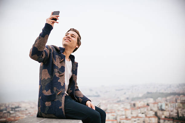 istock Young man his take photo sitting with cityscape 468346718