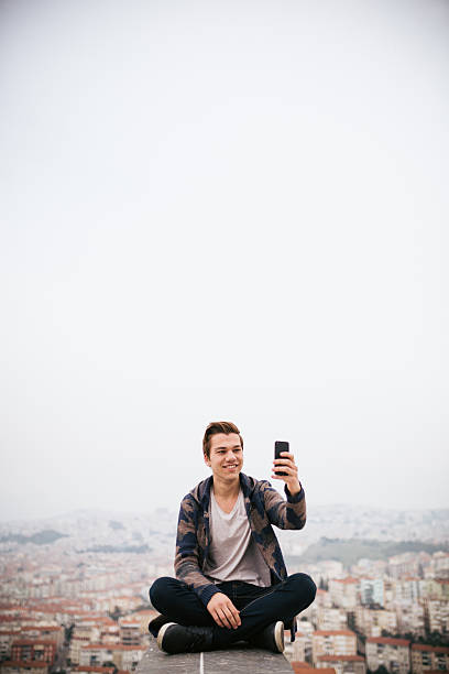 istock Young man his take photo sitting with cityscape 468346728