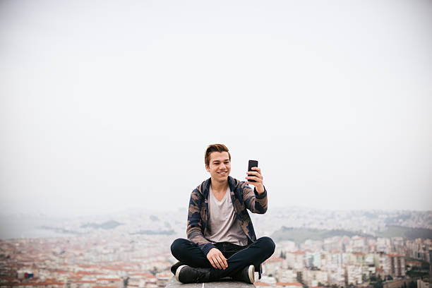 istock Young man his take photo sitting with cityscape 468346732
