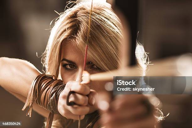Woman Archer Aiming With Bow And Arrow Stock Photo - Download Image Now - Archery, Women, Warrior - Person