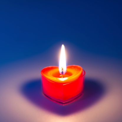 Close-up of a heart shape candle burning.