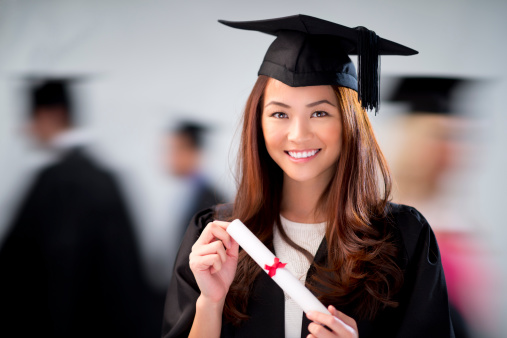 female graduate looks determined with blurred graduates in the background