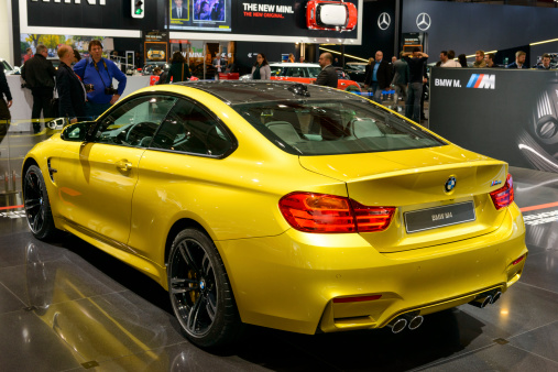 Brussels, Belgium - January 14, 2014: BMW M4 coupe sports car on display at the 2014 Brussels motor show. The M4 is the M Performance version of the BMW 4-series. People in the background are looking at the cars.