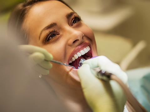 Happy woman having dental procedure with dental drill.