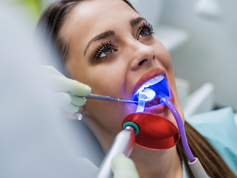 Young woman receiving dental examination with medical laser.