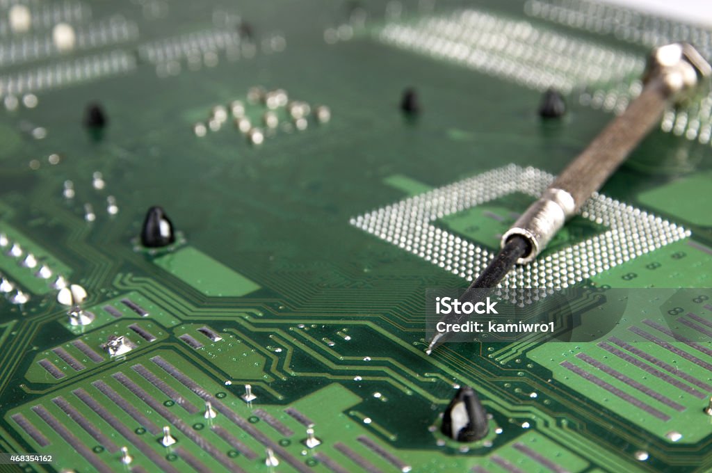 Computer motherboard and Screwdriver. The surface of the old motherboard and small metal Screwdriver. 2015 Stock Photo