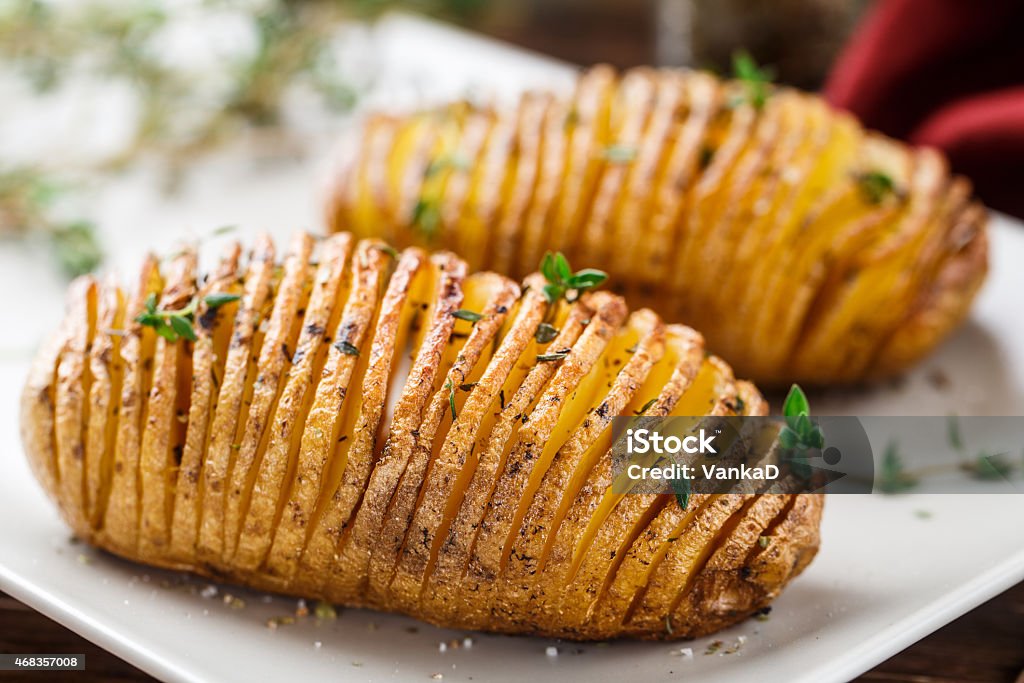 Hasselback potatoes Hasselback potatoes with herbs on a plate Prepared Potato Stock Photo