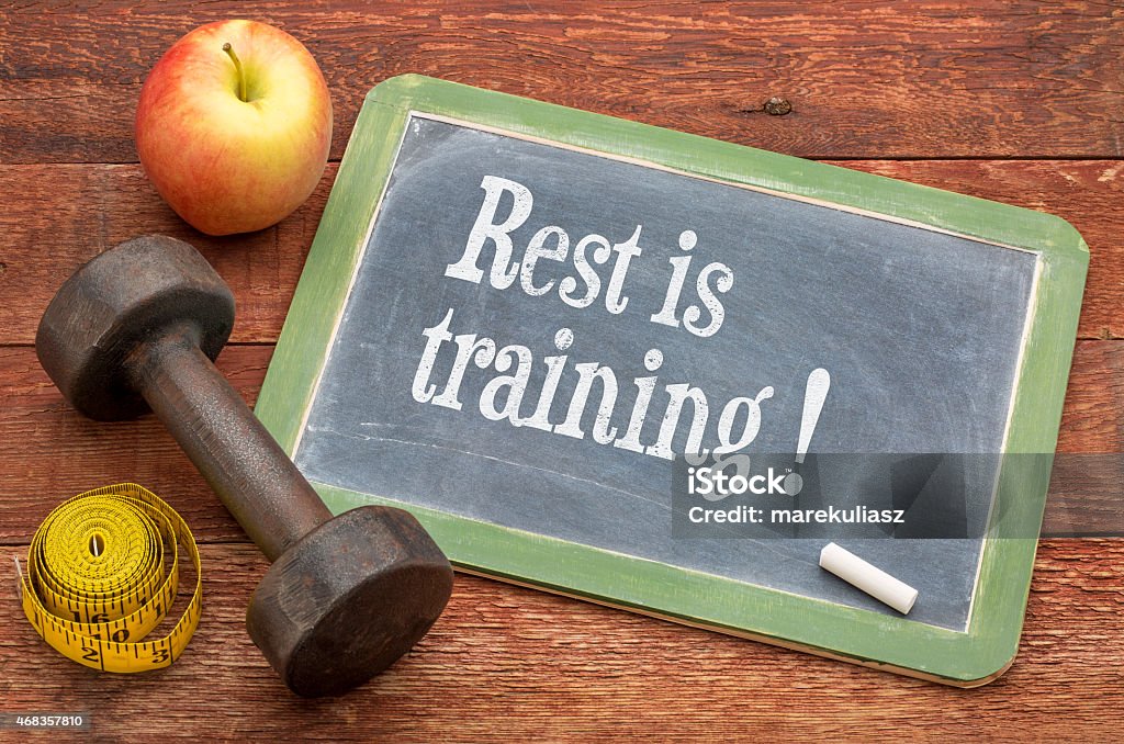 rest is training rest is training - recivery concewpt -  slate blackboard sign against weathered red painted barn wood with a dumbbell, apple and tape measure 2015 Stock Photo