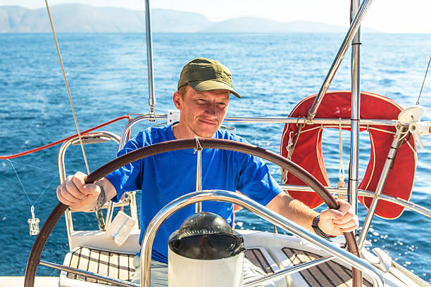 istock Young man skipper at the helm controls sailing yacht. 468359114