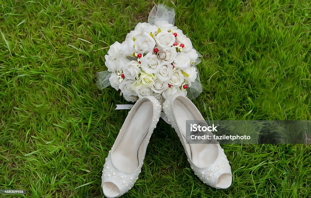bridal bouquet and shoes Close-up on the green grass yellow bridal bouquet of roses in her white shoes on the background 2015 Stock Photo
