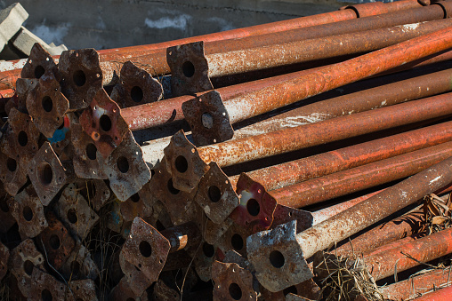 old scaffold tubes storaged outside in a pile. all the tubes have a base plate