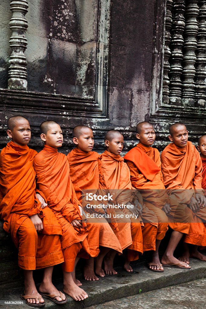 Cambodian Buddist Monks at Angkor Wat Ancient Temple Ruins Angkor Wat, Cambodia - November 8, 2013: A group of cambodian buddhist monks sit in the grounds of the Ancient Angkor Wat Temples. 2015 Stock Photo