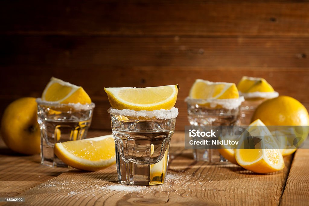 Tequila Tequila in shot glasses with lemon and salt on wooden background. 2015 Stock Photo