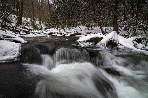 A snow-covered mountain creek flowing through the Great Smoky Mountains National Park in the winter.