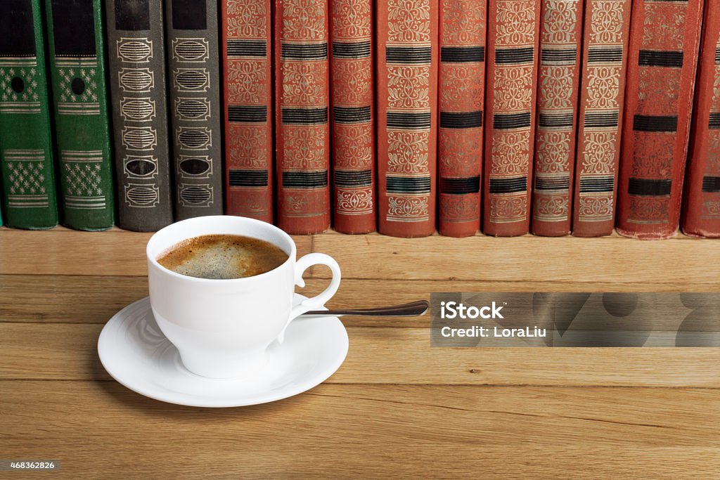 Hot cup of fresh coffee on the wooden table Hot cup of fresh coffee on the wooden table and a stack of books to read 2015 Stock Photo