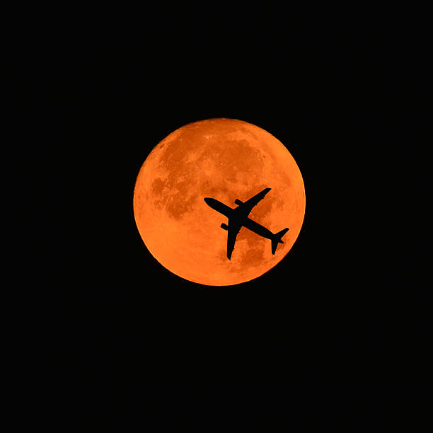 an airplane flying across a full moon