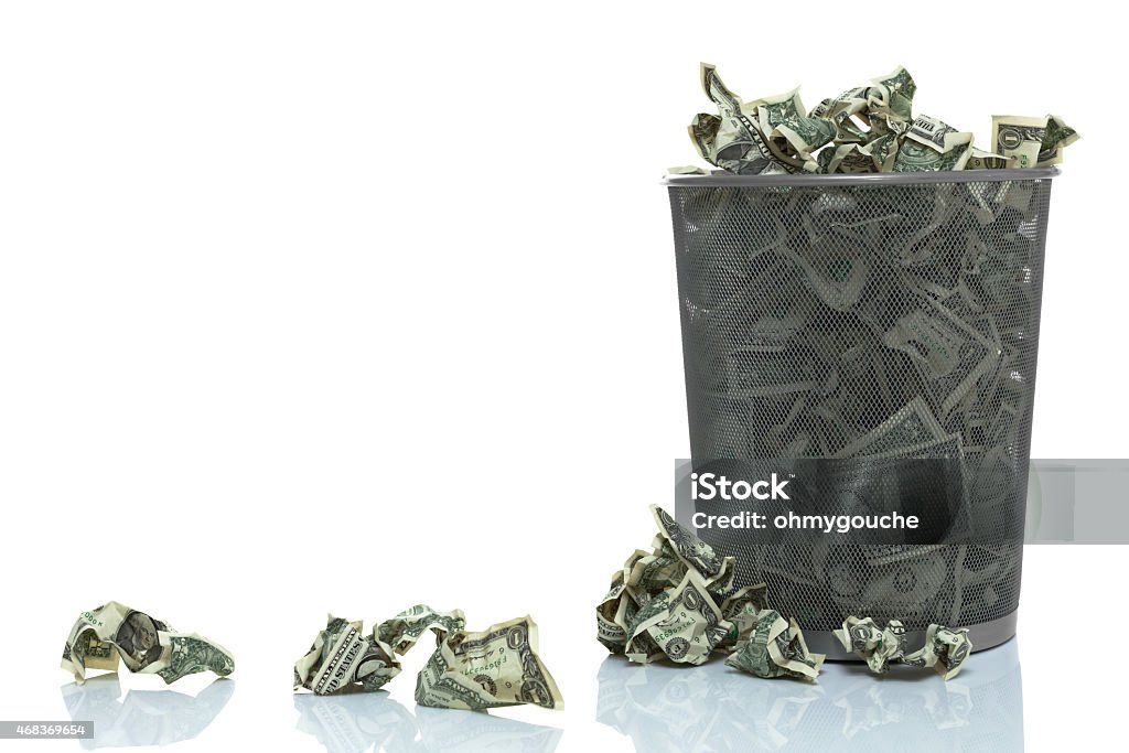 Garbage can full of money spilling over Money to Burn Stock Photo