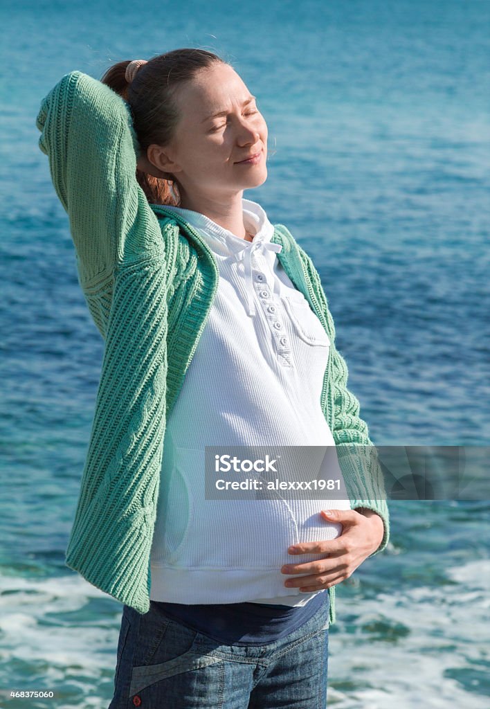 Pregnant woman in the sun on seashore Pregnant woman basking in the sun on seashore 2015 Stock Photo